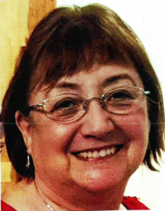 A woman with a dark brown bob and glasses smiles at the camera